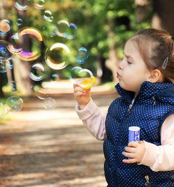 A little girl makes soap bubbles